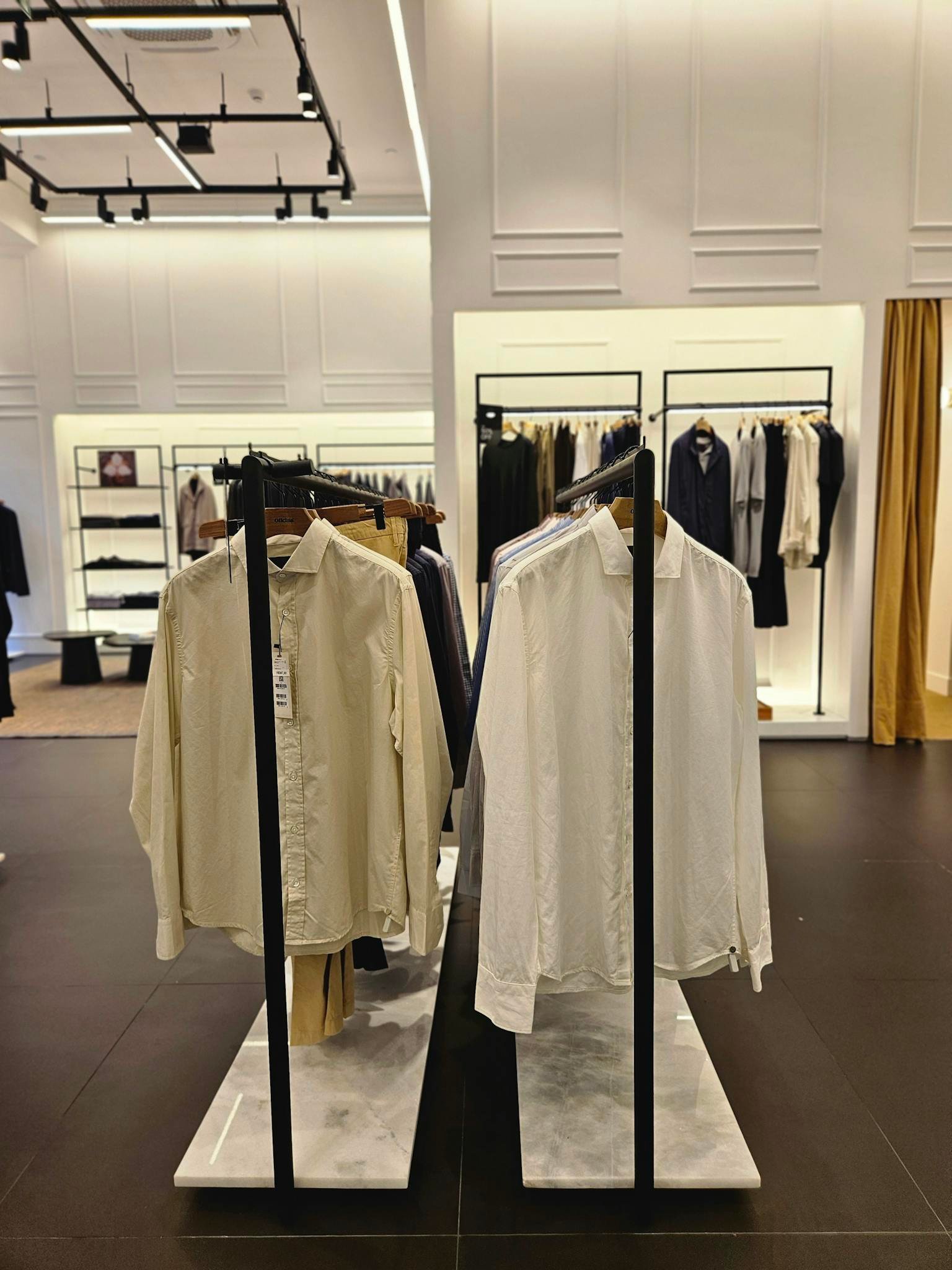 A modern retail store showcasing elegant mens shirts and clothing on display racks.
