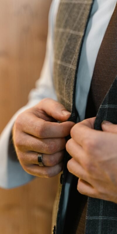 Close-up of a man's hands buttoning a stylish tailored suit, showcasing elegance and craftsmanship.