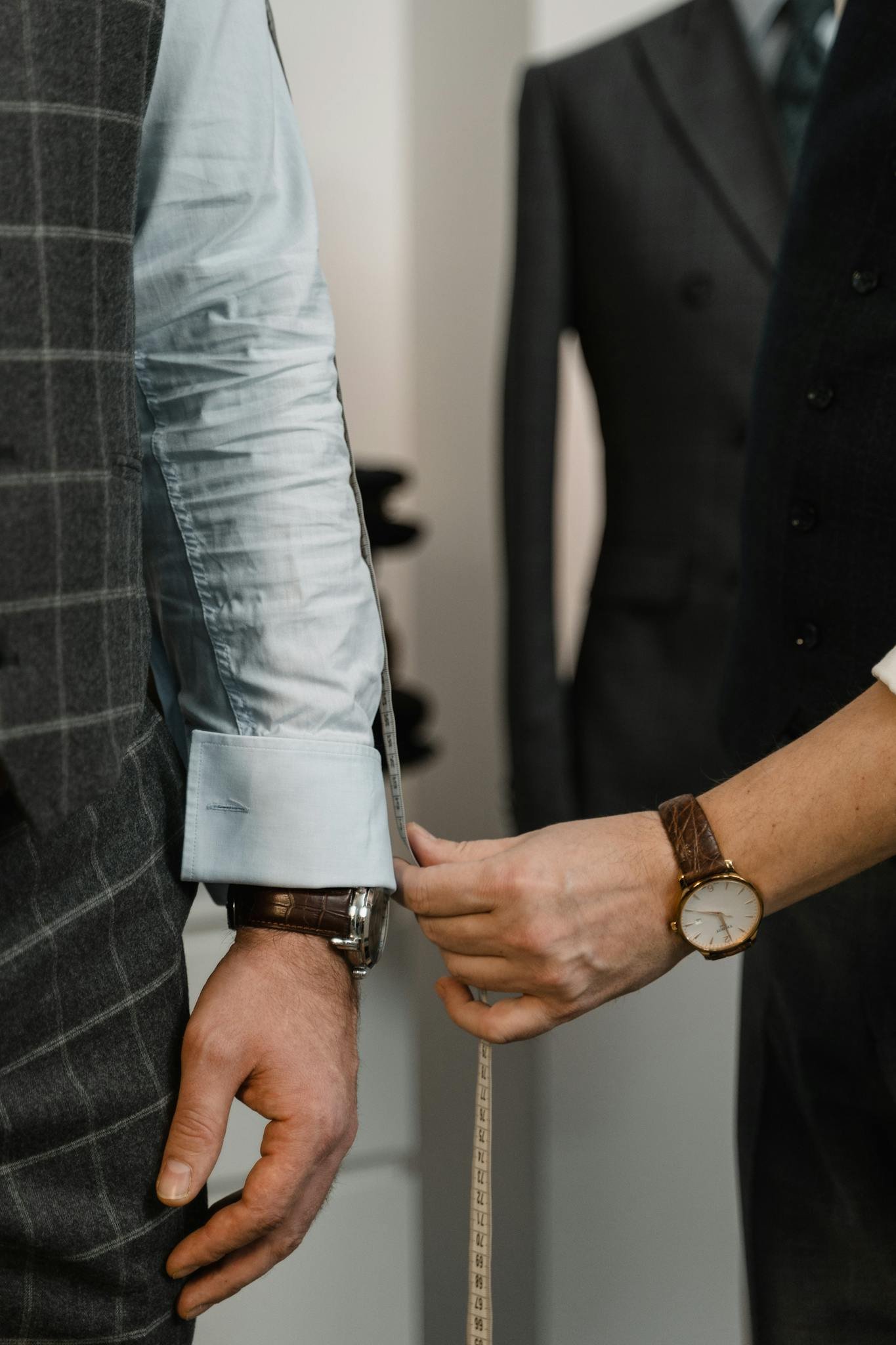 Tailor measuring client's arm for a custom suit in a fashion studio.